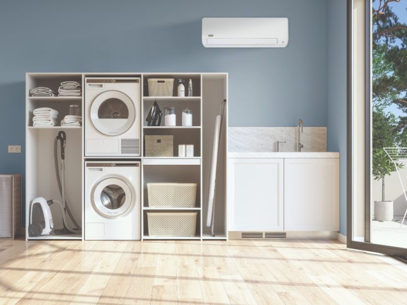 Laundry Room With Beige Wall And Parquet Floor With Washing Machine, Dryer, Laundry Basket And Folded Towels In The Cabinet.